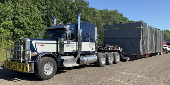 Heavy haul tractor-trailer carrying a tarped oversize load on a lowboy trailer